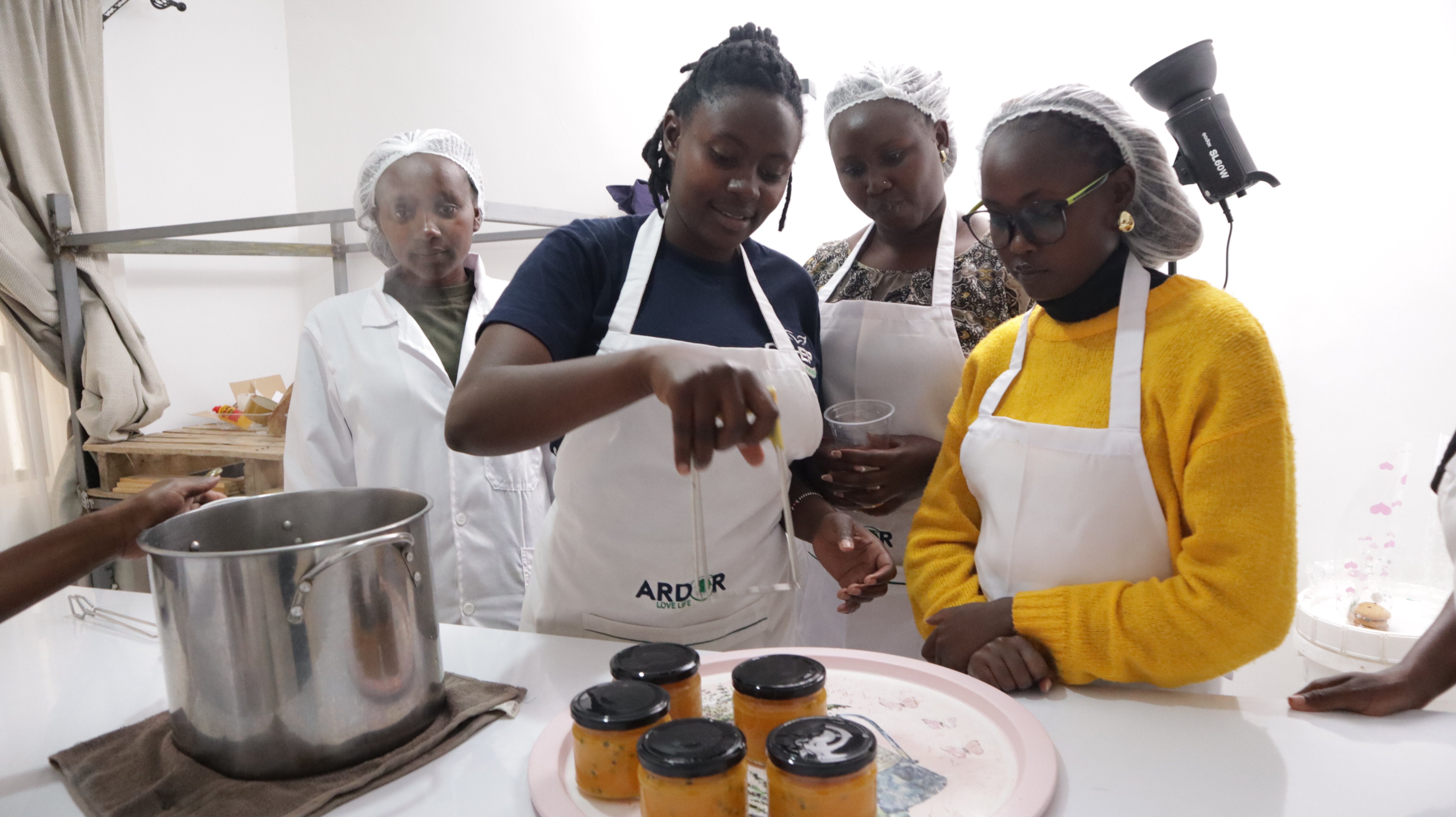 Women in aprons making fruit preserves during a Spring Agric value-addition training